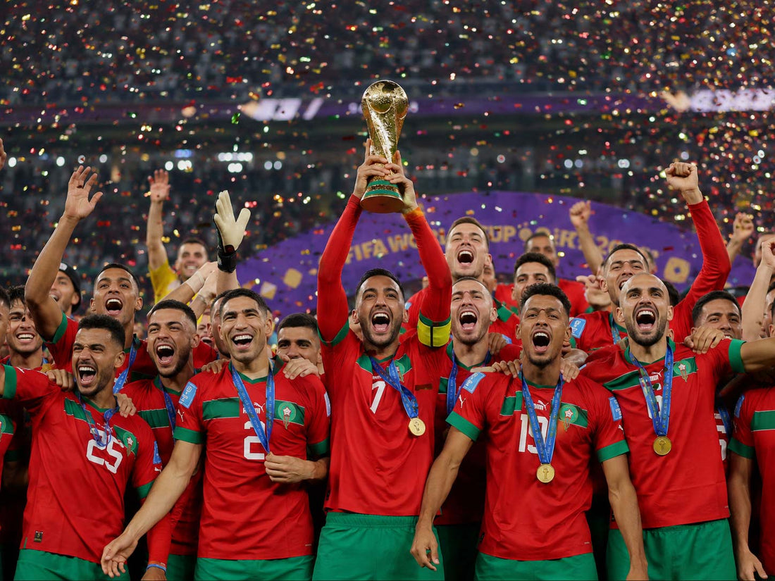 Équipe du Maroc célébrant une victoire en Coupe du Monde 2026, joueurs en maillot rouge soulevant le trophée dans un stade sous les confettis