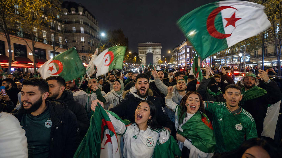 Supporters algériens célébrant dans les rues de Paris, avec drapeaux de l’Algérie, maillots verts et blancs, ambiance de victoire et scène festive nocturne.